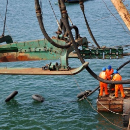 Arbeiter installieren eine Maschine zum legen von Unterwasserkabeln auf einem Schiff