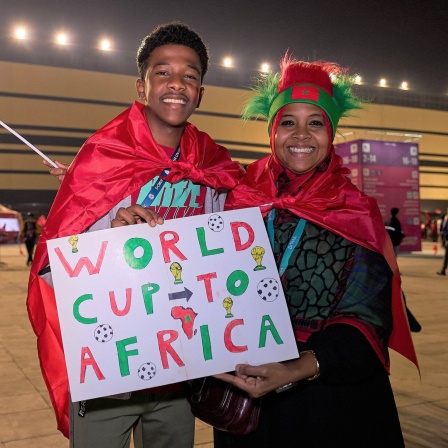 Zwei marokkanische Fans, ein junger Mann und eine Frau, halten ein Schild auf dem steht &#034;World Cup to Africa&#034;