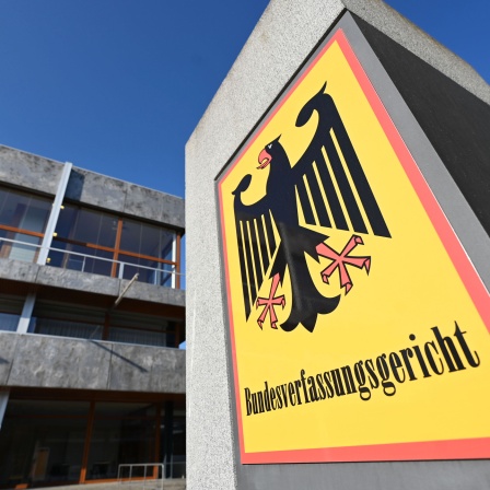 Vor dem Bundesverfassungsgericht hängt ein Hinweisschild mit der Aufschrift Bundesverfassungsgericht und dem Bundesadler.