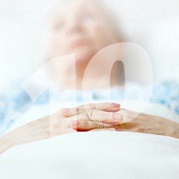 Eine alte Frau liegt mit gefalteten Händen im Sterbebett. Die Zahl Zehn als Wasserzeichen.