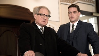 Zwei Männer im Anzug stehen in einem Gerichtssaal