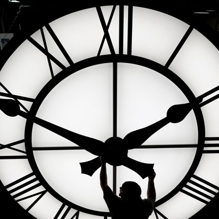 Ein Techniker bewegt die Uhrzeiger einer Uhr mit einem Durchmesser von mehr als 3,5 Metern