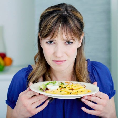 Eine junge Frau riecht an einem Teller Pasta und rümpft die Nase: Riechen ist ein Sinn, der uns schützt. Denn alles, was wir oral, also mit dem Mund, aufnehmen, analysieren wir mit der Nase. So verhindern wir, dass Schadstoffe in unseren Körper gelangen.