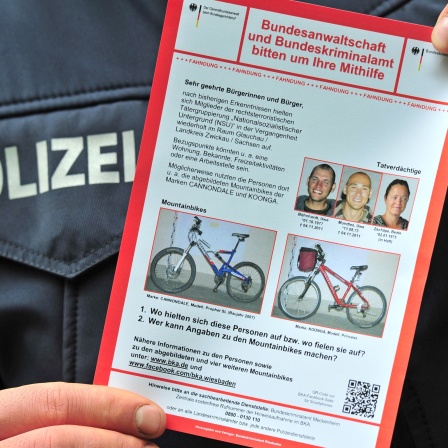 Ein Polizist hält 2012 einen Fahndungsaufruf des Zwickauer Terror-Trios in der Hand.