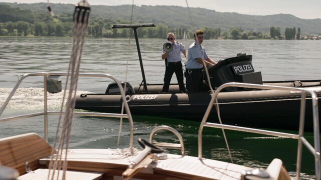Ein Mann auf einem Boot der Wasserschutzpolizei spricht durch ein Megafon.