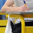 Abiturienten eines Gymnasiums schreiben in einer Turnhalle die Abiturprüfung in Deutsch. 