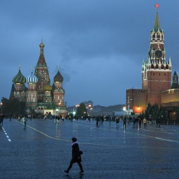 Wenige Passanten gehen am Abend in Moskau bei herbstlichem Nieselregen vor der Kulisse der Basilius-Kathedrale (l) und der Kreml-Mauer über den Roten Platz.