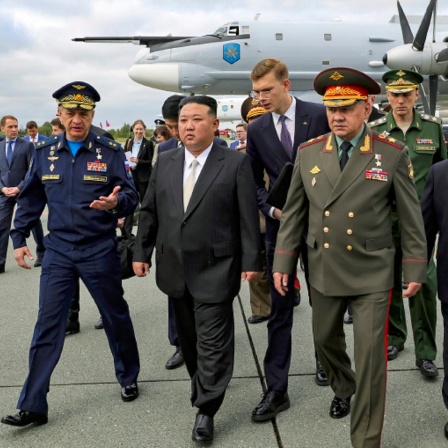 Nordkoreas Machthaber Kim Jong Un (Mitte) und der russische Verteidigungsminister Sergej Schoigu (rechts im Vordergrund) gehen auf dem Flughafen von Wladiwostok, um russische Kampfflugzeuge zu inspizieren.