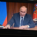 Sie sehen Wladimir Putin. Er spricht.