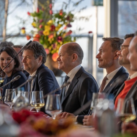 Bundeskanzler Olaf Scholz sitzt unter anderem mit den Ministern Robert Habeck und Christian Lindner an einem großen Tisch. 