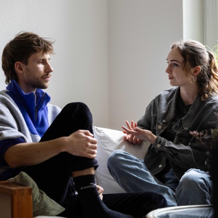 Die Geschwister Emmanuel und Maria Gottschalk unterhalten sich auf einer Couch in der Wohnung des Bruders.