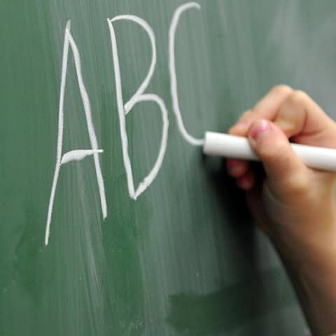Eine Schülerin schreibt das ABC an die Tafel