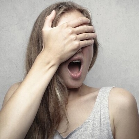 Eine Frau hält sich die Hand vor die Augen.