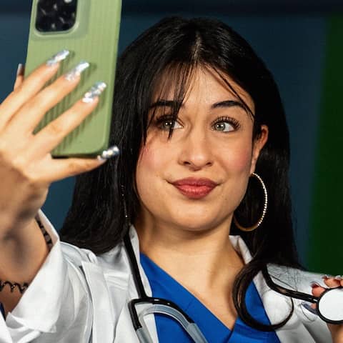 Keyvisual zur Vollbild-Folge &#034;Unseriöse Medfluencer&#034; zeigt eine junge Frau im Arztkittel und mit Stethoskop im Selfie-Modus mit Handy