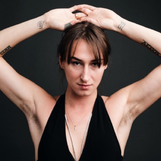 Porträtaufnahme der Schauspielerin Kristina Maca, die die Arme über den Kopf hebt.