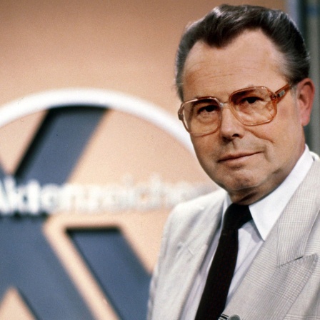 Eduard Zimmermann steht im September 1986 neben dem Logo der Sendung "Aktenzeichen XY ungelöst"
