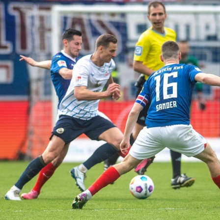 Rostocks Dennis Dressel versucht sich gegen zwei Kieler durchzusetzen. 
