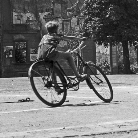 Ein Junge fährt Fahrrad ca. 1945-1955, Freiburg,  im Hintergrund zerstörte Wohnhäuser
