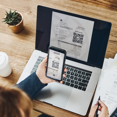 Eine Person scannt mit ihrem Smartphone den QR-Code auf einer digitalen Rechnung.