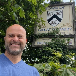 London Korrespondent Christoph Prössl steht vor dem Ortsschild Great Grimsby 
