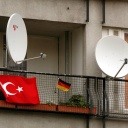 Satellitenschüsseln auf einem Balkon mit deutscher und türkischer Flagge.