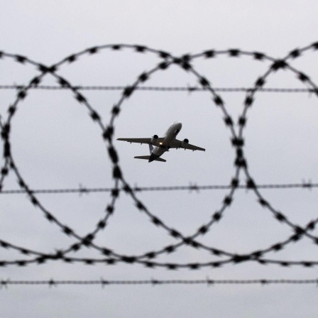 Symbolbild Abschiebung: Flugzeug durch Stacheldrahtzaun