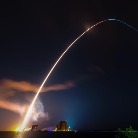 Eine Rakete starten im Weltraumbahnhof Cape  Canaveral. Der Schweif zieht einen langen Bogen in den Nachthimmel.