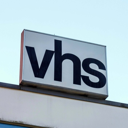 Auf einem Dach ist das Schild "VHS" zu sehen.