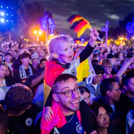 Die dreijährige Jolie (Mitte) jubelt mit ihren Eltern in der Fanzone am Brandenburger Tor beim Eröffnungsspiel der Fußball-EM (Bild: picture alliance/dpa/Christoph Soeder)