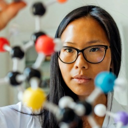 Eine junge Wissenschaftlerin betrachtet ein DNA-Modell im Labor.
