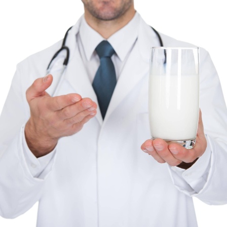 Arzt zeigt auf ein Glas Milch: Stimmt es, dass man Antibiotika nicht mit Milch einnehmen sollte?