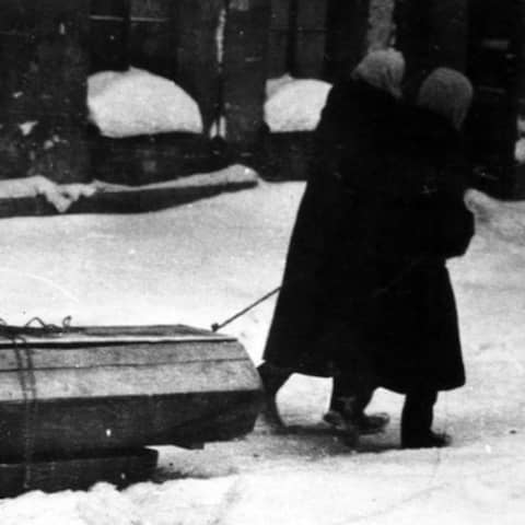 Während der Blockade von Leningrad (1941 - 1944) ziehen zwei Frauen einen Sarg auf einem Schlitten durch den Schnee