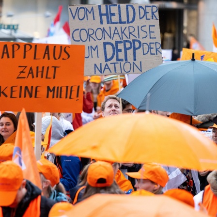 Teilnehmerinnen und Teilnehmer eines Warnstreiks der Gewerkschaft Marburger Bund nehmen an einer Demonstration teil und halten Plakate mit der Aufschrift &#034;Applaus zahlt keine Miete&#034; und &#034;Vom Held der Coronakrise zum Depp der Nation&#034; in den Händen.
