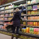 Eine Frau greift im Supermarkt in ein Kühlregal mit Säften