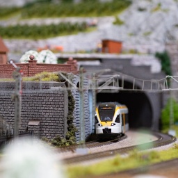 Modellbau: Ein Zug der Eurobahn fährt auf Schienen durch einen Tunnel in einer Miniaturlandschaft.