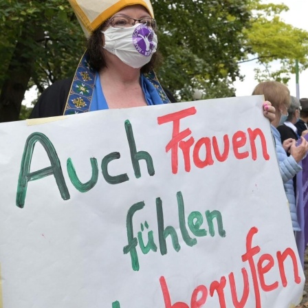 Demonstrantin vor der Regionalkonferenz des Synodalen Weges in Ludwigshafen. Sie trägt ein Transparent mit der Aufschrift "Auch Frauen fühlen sich berufen". © Synodaler Weg /  Klaus Landry