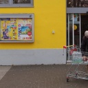 Älterer Mann mit Einkaufswagen vor einem Supermarkt