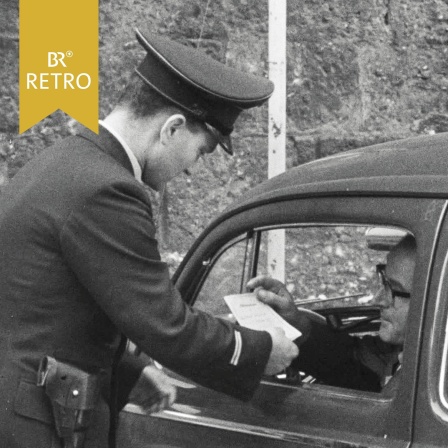 Polizist kontrolliert den Führerschein eines Autofahrers | Bild: BR Archiv