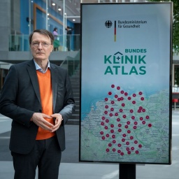 Gesundheitsminister Karl Lauterbach steht vor einem Plakat für den Bundes-Klinik-Atlas.