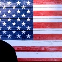 Donald Trump steht mit gesenktem Kopf vor einer US-Flagge