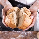 Männerhände brechen ein frisches Brot in der Mitte
