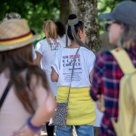 Eine Demonstrantin trägt ein T-Shirt mit dem Text "Gib Gates keine Chance" in Baden-Baden. 