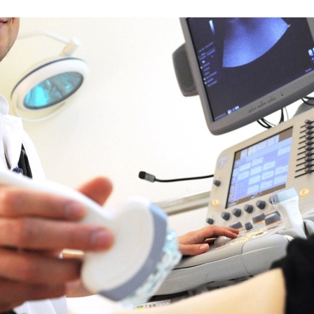 Ein Arzt hat ein Ultraschallgerät in der Hand.