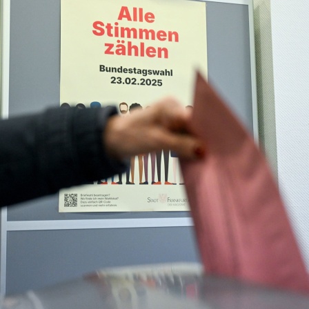 Eine Frau wirft im Briefwahllokal ihren Briefwahlumschlag zur Bundestagswahl in die Wahlurne. 