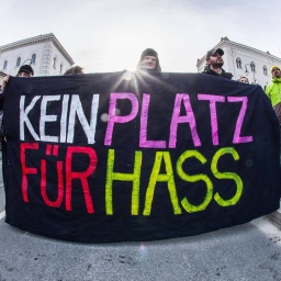 Ein Plakat auf einer Demo für die Demokratie in München wird gezeigt. Auf schwarzen Hintergrund steht in großen, bunten Lettern "KEIN PLATZ FÜR HASS".