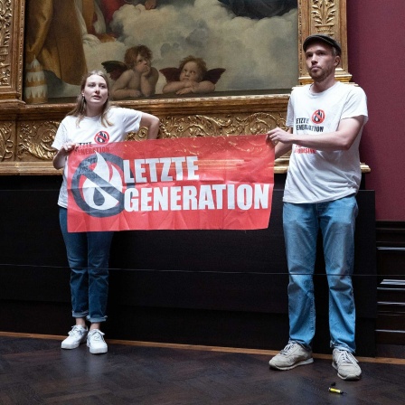 Zwei Umweltaktivisten der Gruppe "Letzte Generation" stehen in der Gemäldegalerie Alte Meister an dem Gemälde Sixtinische Madonna von Raffael. 