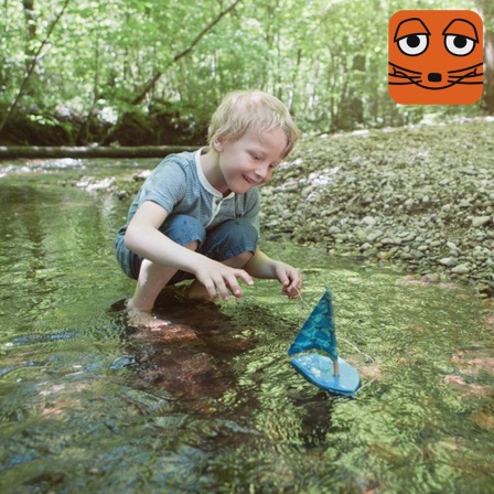 Zwei Jungs an einem Bach im Wald mit Bootchen