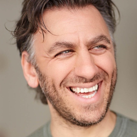 Der Schauspieler und Comedian Cem Ali Gültekin lacht auf einem Porträt
