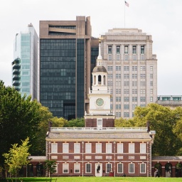 Die Independence Hall von Philadelphia in den USA, im Hintergrund Hochhäuser, davor eine grüne Wiese