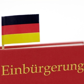 Buch mit Aufschrift Einbürgerung und Deutschlandfahne als Lesezeichen